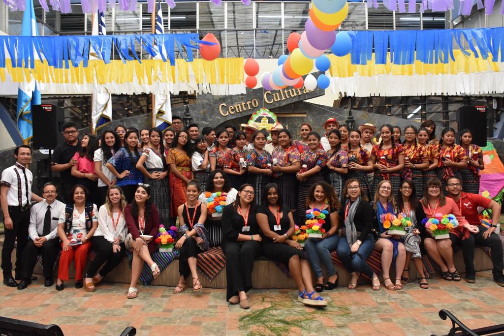 La fotografía muestra el encuentro entre estudiantes de FAUSAC, Guatemala, y los visitantes de la UPR-Río Piedras, Puerto Rico. La foto muestra las personas organizadas en dos filas. En la línea superior, están las personas participantes de Guatemala; en la inferior, las personas participantes de la UPR-Río Piedras. La fotografía fue tomada frente al Centro Cultural.